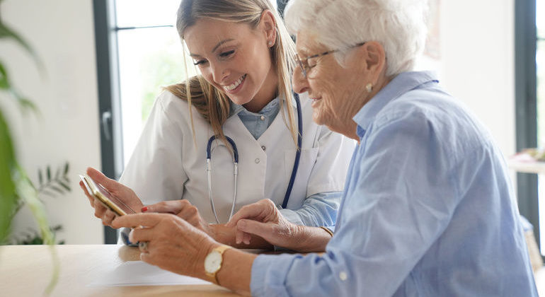 Elderly_woman_with_nurse_at_home_looking_at_tablet