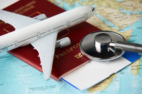 Boarding_pass_and_a_passport_travel_documents_with_medical_stethoscope_and_airplane_on_world_map_background,_close-up._Medical_travel_concept