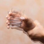 Closeup_view_on_the_shaking_hand_of_a_person_holding_drinking_glass_suffering_from_Parkinson's_disease