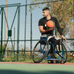 Young_handsome_man_in_wheelchair_at_basketball_playing_ground_