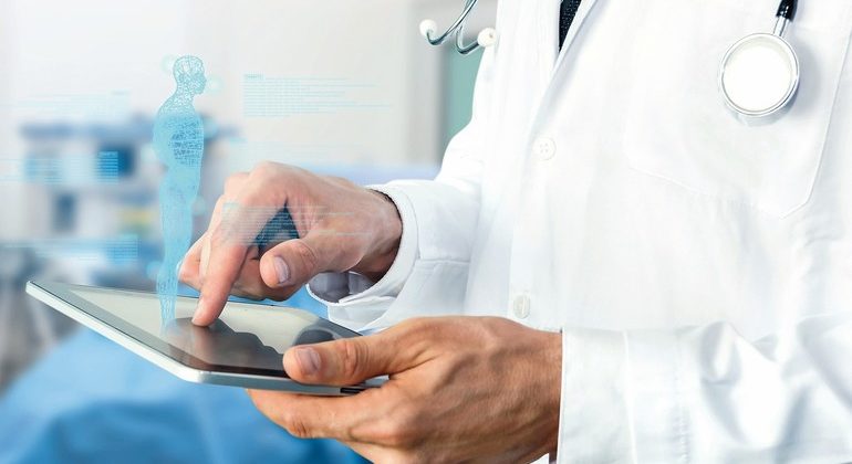 Smart_health_care_internet_of_things_and_hospital_automation_management_,_Artificial_intelligence_hologram_robot_adviser_technology_concept._Doctor_with_Stethoscope_using_tablet_for_remote_monitoring.